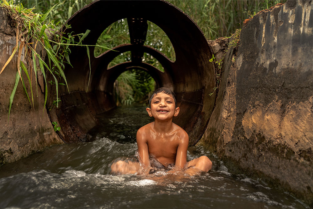 Samir smiling and sitting in a water pipe after cleft surgery