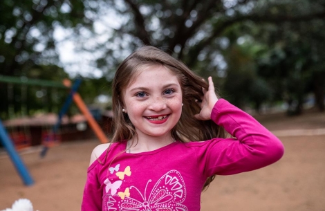 Milena smiling on a playground, tossing her hair back